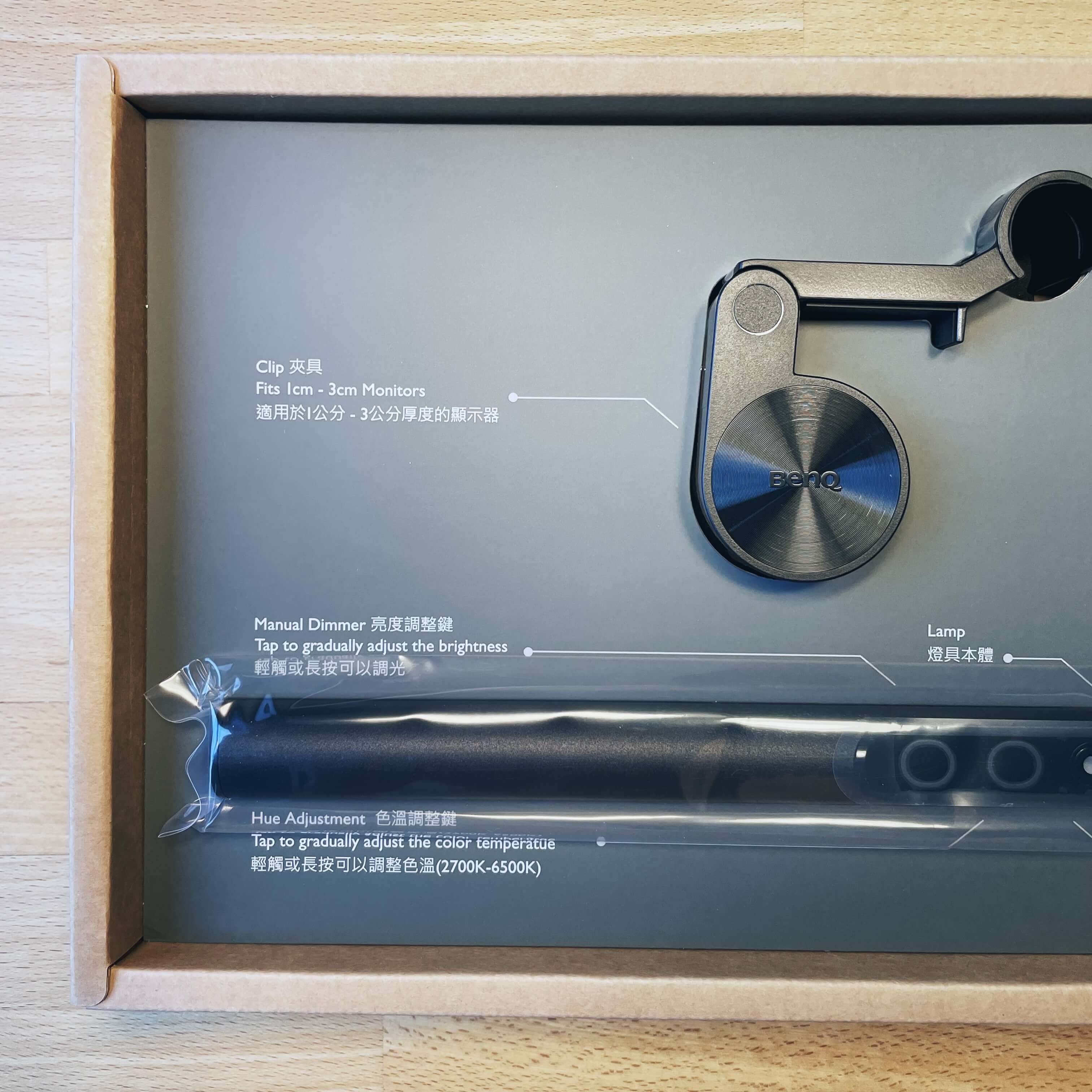 Photo showing a part of the internals of the packaging. The clip, the left side of the lamp and some packaging instructions are shown.